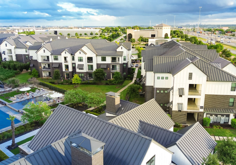 White multi-family buildings circle a pool and large yards.